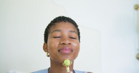 African woman enjoying jade roller facial for glowing skin and relaxation