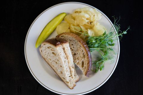 Toasted Sourdough Sandwich featuring Pickle, Potato Chips and Microgreens on White Plate