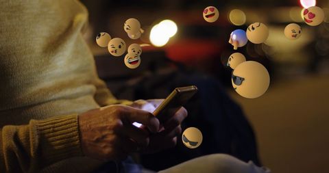 Creative emojis emanating from smartphone at night