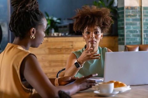 African american colleagues collaborating in cafe over laptop, coffee and pastry