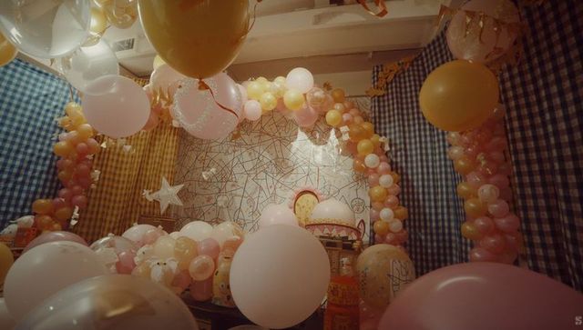 Pastel balloon arch framing geometric mural party corner, metallic star, gingham drapes