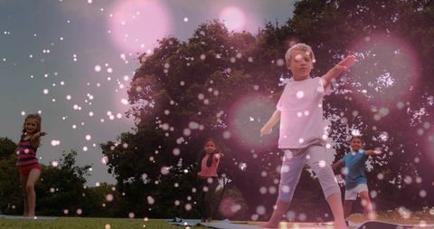 Kids practicing outdoor yoga with pink bokeh effect, balancing on mats in park greenspace
