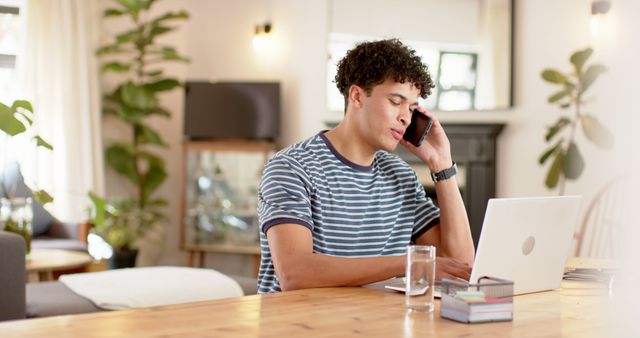 Young Man Working from Home using Laptop and Phone - Download Free Stock Images Pikwizard.com