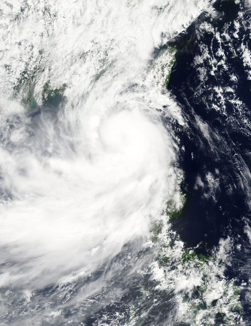 This satellite image captures Tropical Storm Linfa over the South China Sea on July 7, showing intense thunderstorms wrapping into the storm's center. The storm strengthened as it moved away from northern Philippines, nearing Hong Kong and southern Taiwan. Ideal for use in weather reports, educational materials on meteorology, or emergency preparedness content.