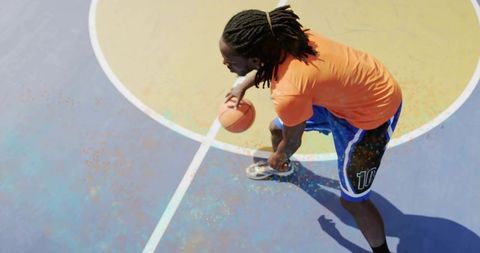 High-angle dribbling on vibrant two-tone outdoor basketball court, athlete in motion