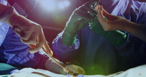 Surgical team performing precise open surgery with gloved hands and scalpel close-up