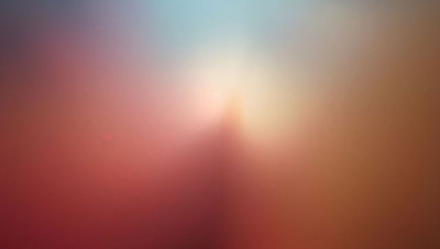 Soft-focus gradient with central glow and triangular blur in red-orange to blue tones