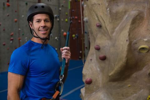 Male climber with safety gear at indoor climbing wall in gym