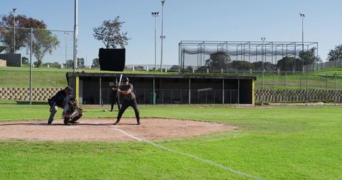 Baseball Batter Preparing to Swing on Community Field with Catcher and Umpire, Dugout Behind