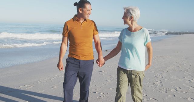 Happy senior caucasian couple holding hands and walking on beach. Senior lifestyle, realxation, nature, free time and vacation.