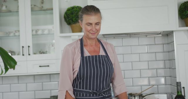 Senior Woman Cooking in Modern Kitchen Wearing Striped Apron - Download Free Stock Images Pikwizard.com