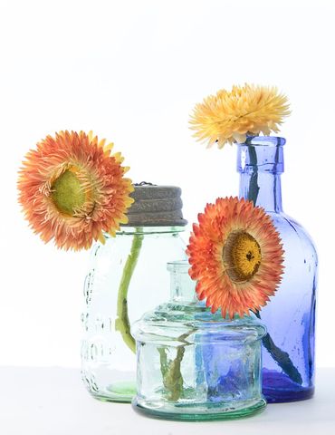Colorful glass bottles with vibrant orange and yellow flowers