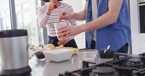 Diverse Couple Preparing Fresh Juice Together in Modern Kitchen