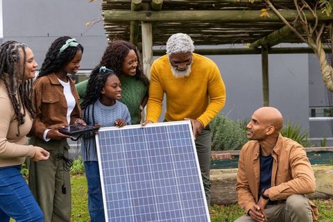 Multigenerational family learning solar panel installation under pergola in urban garden