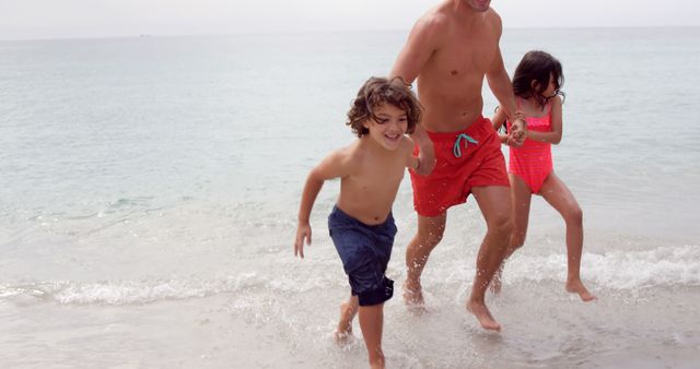 Family Enjoying Beach Day, Father Playing with Daughter and Son in Water - Download Free Stock Images Pikwizard.com