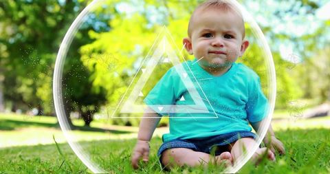 Curious baby sitting on green grass in sunny park with digital geometric circle triangle overlay