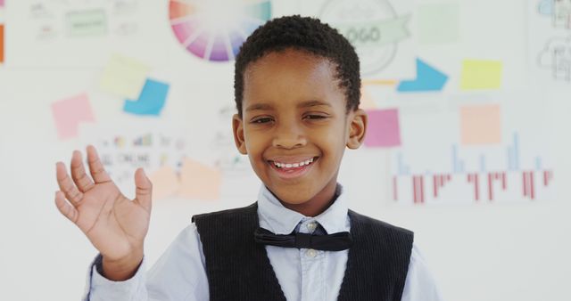 Smiling Boy in Bow Tie Waving in Classroom Setting - Download Free Stock Images Pikwizard.com