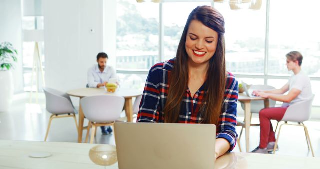 Smiling Woman Working on Laptop in Modern Co-working Space - Download Free Stock Images Pikwizard.com