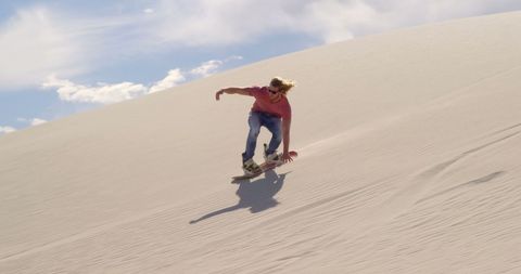 Adventurous Sandboarding Down Desert Dune with Clear Sky