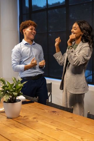 Young diverse coworkers celebrating success and teamwork in modern conference room