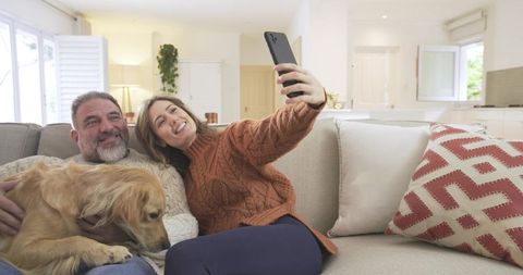 Happy Couple Taking Selfie With Dog on Cozy Living Room Sofa
