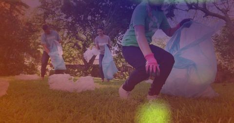 Volunteers picking up litter in park wearing gloves and holding trash bags