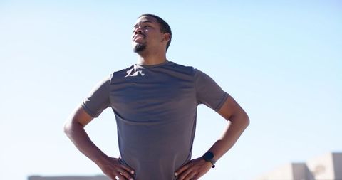African American man standing on rooftop looking up confident athletic lifestyle in city