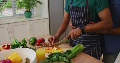 Gay Couple Embracing While Preparing Vegetables in Modern Kitchen