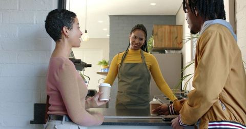African American Barista Serving Customers at Coffee Counter with Takeaway Cups