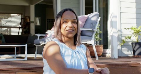 Senior african american woman relaxing on porch steps wearing smartwatch and light blouse