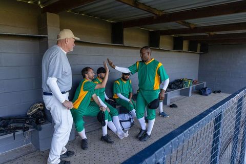 Baseball team high-fiving in dugout celebrating teamwork and camaraderie