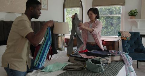 Couple Packing for Vacation in Cozy Bedroom Setting