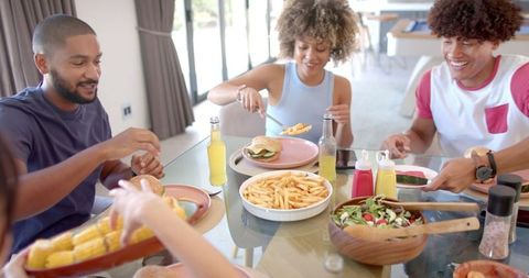 Friends Enjoying Casual Meal with Burgers and Fries at Home Dining Table