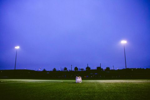 Soccer team huddled under stadium lights at dusk
