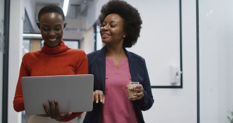 Professionally dressed women collaborating in modern office hallway