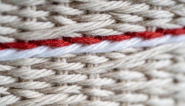 Macro braided natural twine with red and white stripe showing textured woven beige yarn