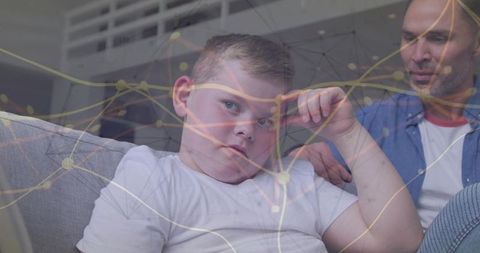 Pensive boy on sofa with father nearby digital network overlay suggesting family connection