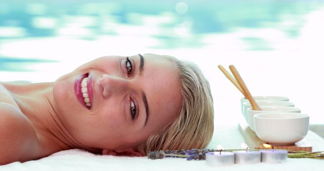 Peaceful smiling blonde lying on massage table poolside outside at the spa