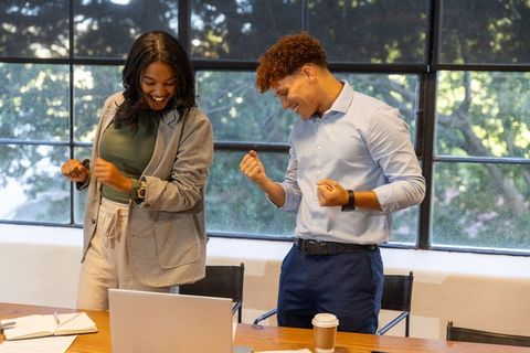 Diverse team celebrating project milestone in bright glass-walled conference room