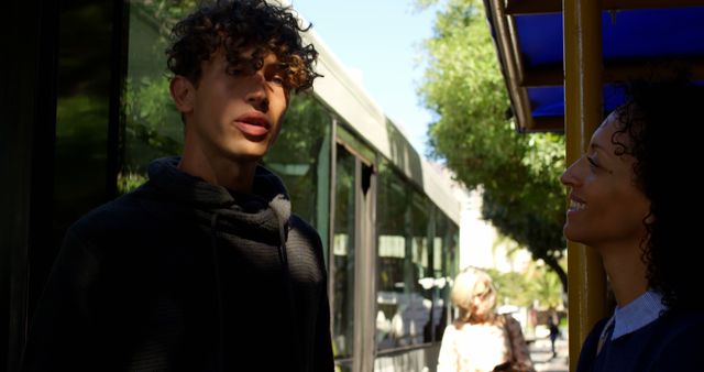 Young Man and Woman Conversing Outdoors Near Bus Stop - Download Free Stock Images Pikwizard.com