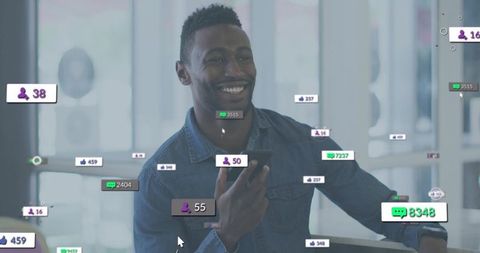 Smiling professional holding smartphone in glass workspace with social media notifications
