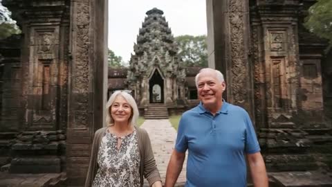 Senior Couple Walking Through Ancient Temple Gateway, Exploring Cultural Heritage