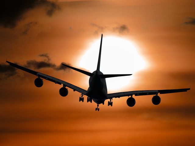 silhouette of a airplane flying in the sunset sky. air travel concept

