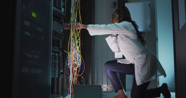 Female IT technician connecting network cables in a server room. This image can be used in articles covering women in technology, IT infrastructure, data centers, and information technology careers.