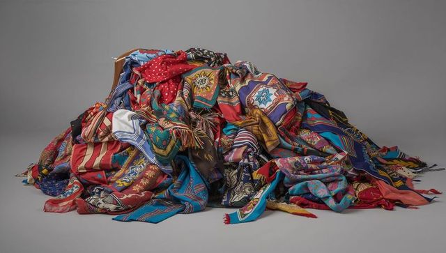 Vibrant patterned silk scarves draping in colorful pile with tassels and fringe