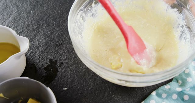 Close-up of woman adding butter cubes to batter in bowl 