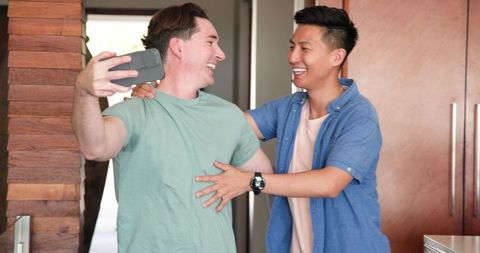 Smiling Diverse Male Couple Taking Selfie and Bonding at Home