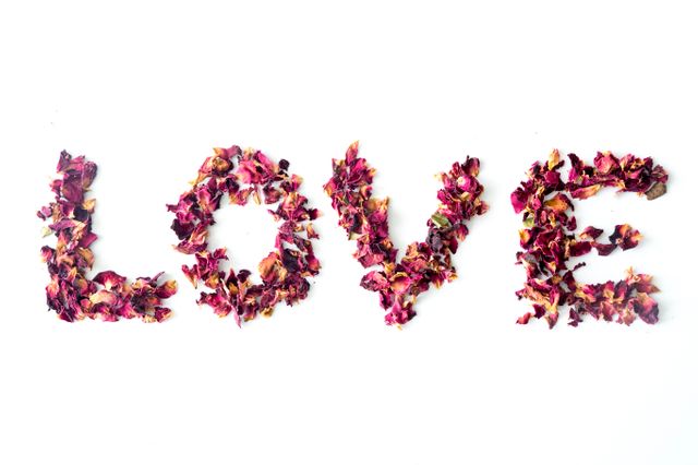 LOVE is creatively spelled out using dried rose petals on a simple, white background. Perfect for romantic messaging, Valentine's Day cards, wedding invitations, or home decor reflecting love and care.