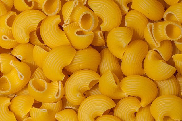 This vibrant close-up of uncooked macaroni pasta is ideal for food blogs, restaurant menus, cooking websites, and recipe books. It works well as a background image for culinary themes or as part of advertisements for pasta brands and food-related products.