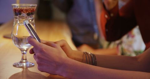 Young Woman Using Smartphone During Social Gathering